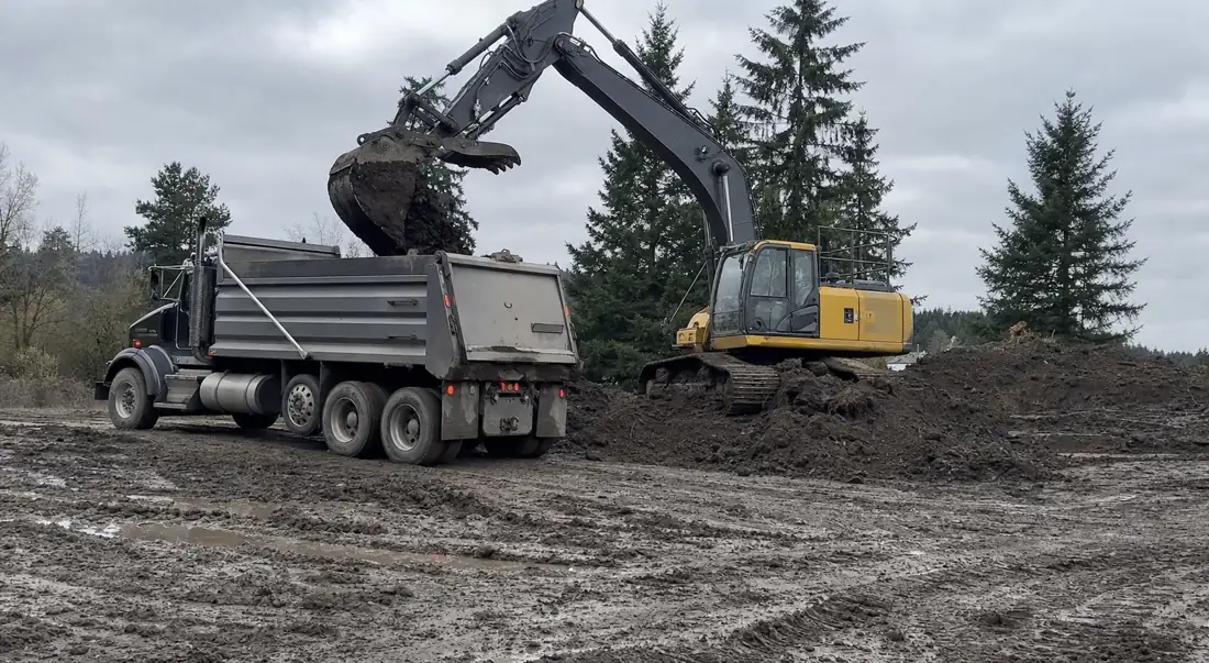 Dump truck being loaded with soil by an excavator for dirt hauling in Hillsboro, OR